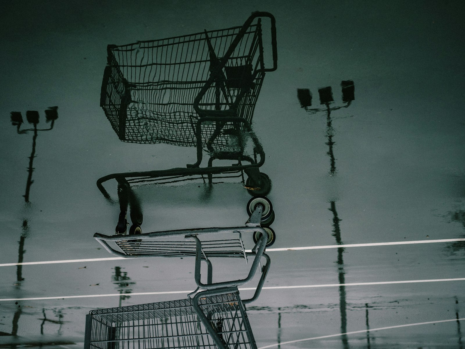Reflection of a shopping cart in rainy parking lot